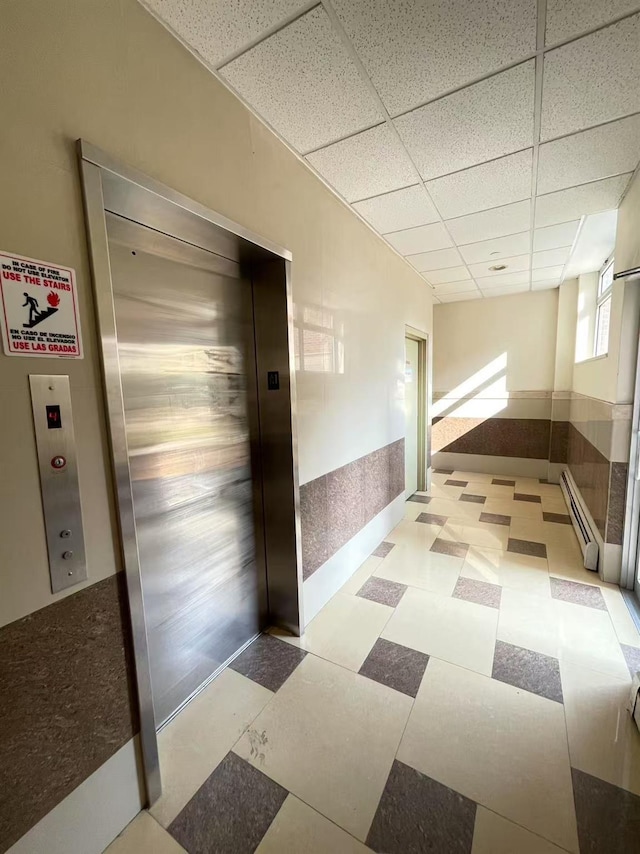 40-48 97th St Unit 1B, Corona, NY 11368 - hallway with a paneled ceiling, elevator, light floors, and a baseboard heating unit