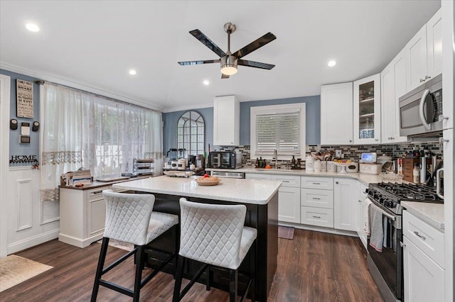 7 Pine Tree Dr, Shirley, NY 11967 - kitchen featuring appliances with stainless steel finishes, decorative backsplash, ceiling fan, a kitchen bar, and white cabinetry