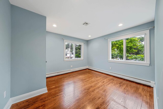 53 Pequot Ln, East Islip, NY 11730 - unfurnished room featuring healthy amount of natural light, wood finished floors, baseboard heating, recessed lighting, and a baseboard heating unit