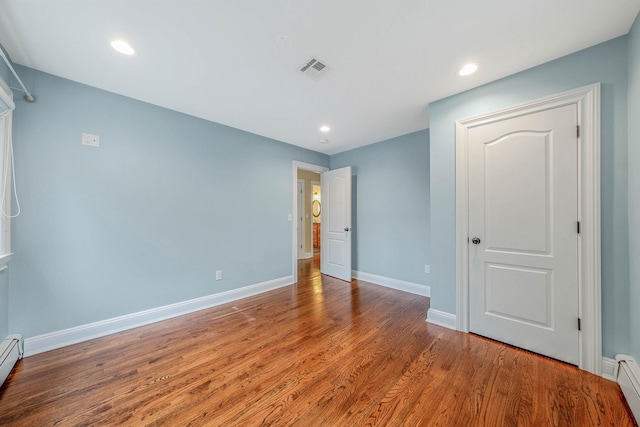 53 Pequot Ln, East Islip, NY 11730 - unfurnished bedroom with wood finished floors, baseboard heating, and recessed lighting