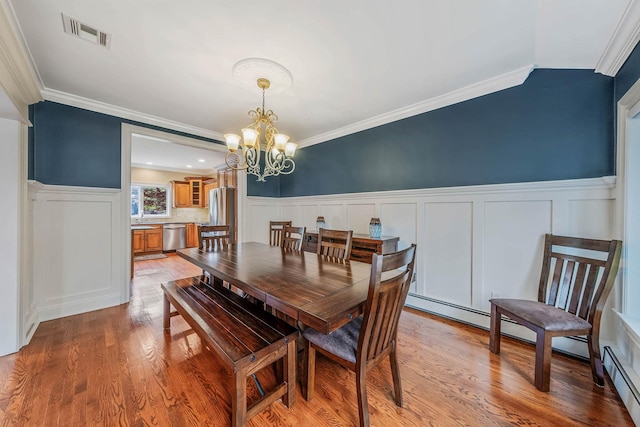 53 Pequot Ln, East Islip, NY 11730 - dining area featuring a decorative wall, a wainscoted wall, a chandelier, light wood finished floors, and crown molding