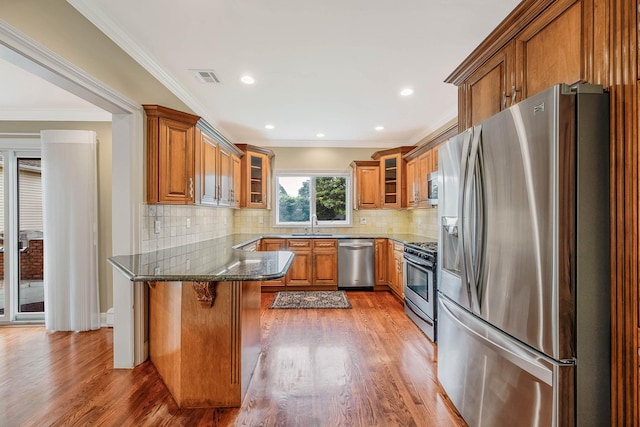 53 Pequot Ln, East Islip, NY 11730 - kitchen with stainless steel appliances, a peninsula, brown cabinets, dark stone countertops, and wood finished floors