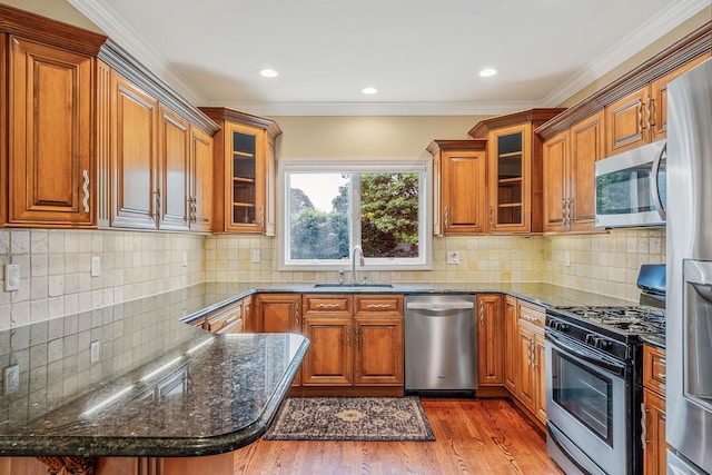 53 Pequot Ln, East Islip, NY 11730 - kitchen featuring stainless steel appliances, brown cabinets, wood finished floors, dark stone counters, and crown molding