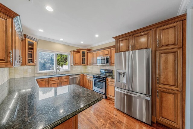 53 Pequot Ln, East Islip, NY 11730 - kitchen featuring stainless steel appliances, brown cabinetry, glass insert cabinets, crown molding, and a peninsula