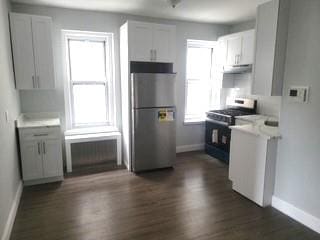 88-11 Elmhurst Ave Unit D15, Elmhurst, NY 11373 - kitchen featuring freestanding refrigerator, black gas stove, radiator heating unit, under cabinet range hood, and dark wood-type flooring