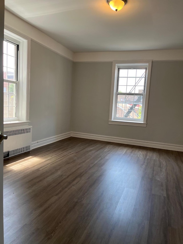 88-11 Elmhurst Ave Unit D15, Elmhurst, NY 11373 - empty room featuring radiator heating unit, plenty of natural light, and dark wood-type flooring