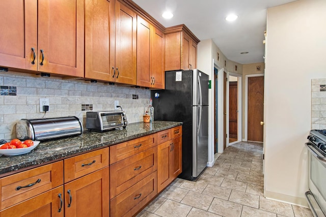 2088 Virgil Pl, Bronx, NY 10473 - kitchen featuring range with gas cooktop, brown cabinetry, freestanding refrigerator, dark stone countertops, and recessed lighting