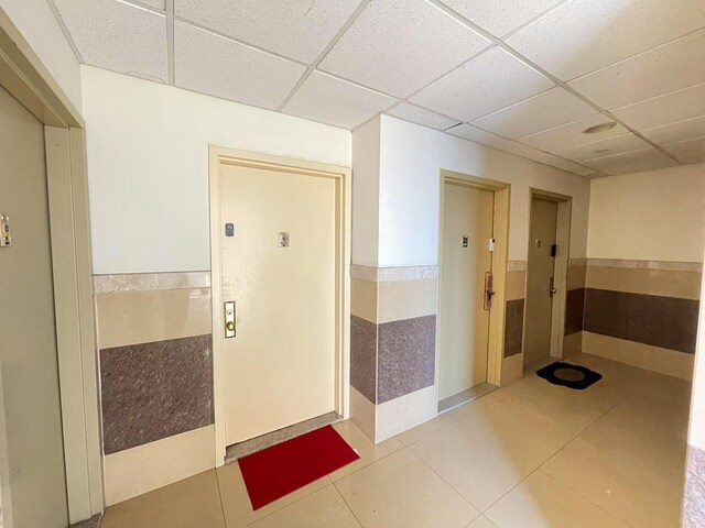 40-48 97th St Unit 2E, Corona, NY 11368 - corridor with a drop ceiling, tile patterned flooring, and a wainscoted wall