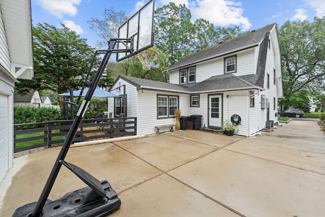 17 Sachem St, East Rockaway, NY 11518 - rear view of house featuring a shingled roof, a patio, a chimney, and concrete driveway