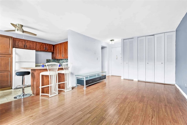 68-15 Selfridge St Unit 5D, Forest Hills, NY 11375 - kitchen with freestanding refrigerator, light countertops, a ceiling fan, light wood finished floors, and a kitchen bar