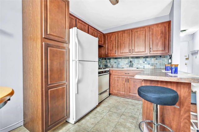 68-15 Selfridge St Unit 5D, Forest Hills, NY 11375 - kitchen featuring white appliances, decorative backsplash, a peninsula, a kitchen bar, and brown cabinets