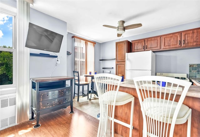 68-15 Selfridge St Unit 5D, Forest Hills, NY 11375 - kitchen with freestanding refrigerator, a breakfast bar, a ceiling fan, and brown cabinetry