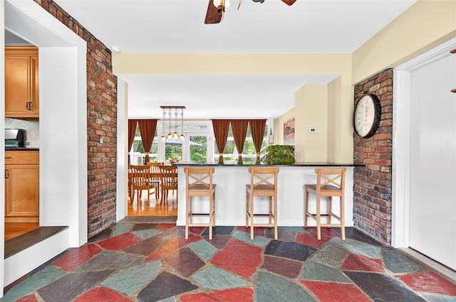 85 Jay St, Stony Point, NY 10980 - kitchen with dark countertops, decorative backsplash, dark stone finish flooring, a breakfast bar, and a ceiling fan