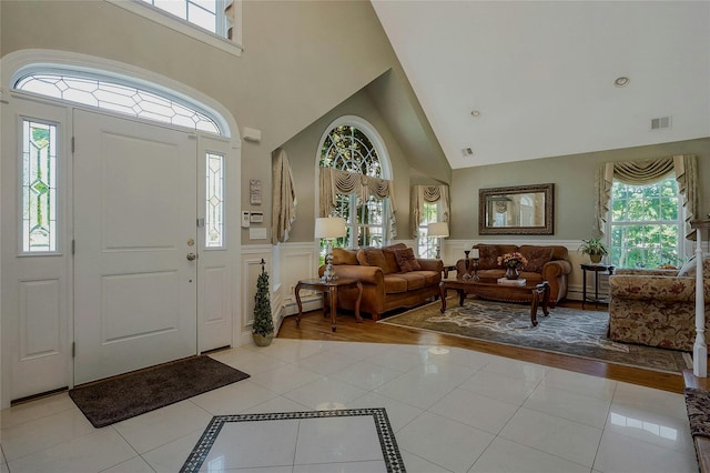 26 Sesame St, Kings Park, NY 11754 - entryway with high vaulted ceiling, wainscoting, light tile patterned floors, inlaid floor details, and a baseboard radiator