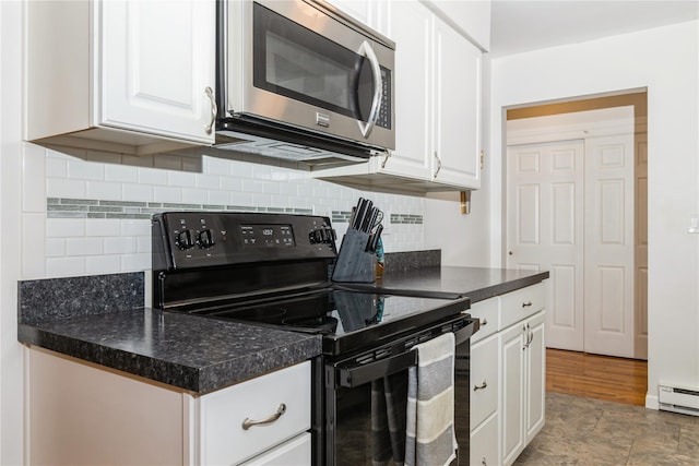 1 Germonds Vlg Unit 16, Bardonia, NY 10954 - kitchen featuring black electric range oven, stainless steel microwave, white cabinets, dark countertops, and baseboard heating