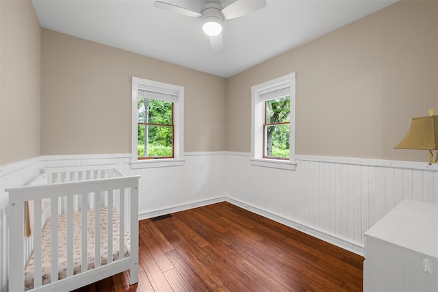 342-344 Van Wagner Rd, Poughkeepsie, NY 12603 - unfurnished bedroom featuring wainscoting, a crib, dark wood-style flooring, and ceiling fan