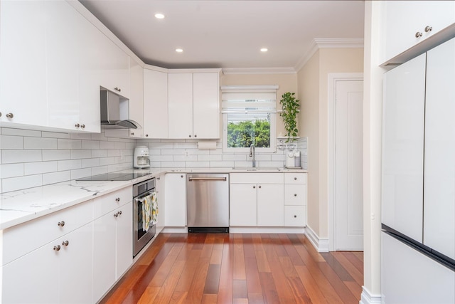 79 Fern St, New Rochelle, NY 10801 - kitchen with appliances with stainless steel finishes, wood finished floors, decorative backsplash, white cabinets, and ornamental molding