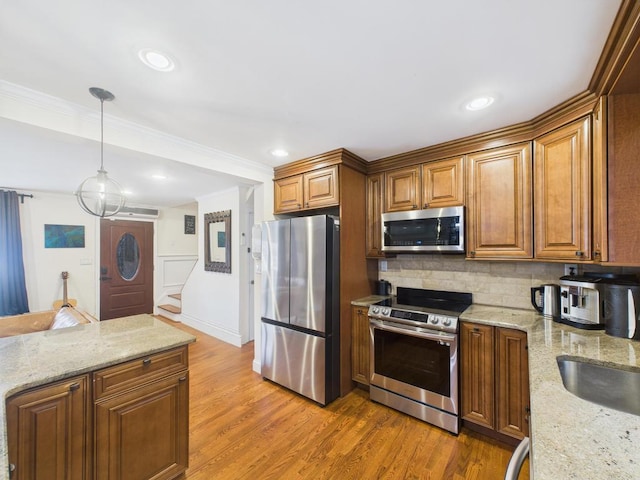 260 9th St, Bethpage, NY 11714 - kitchen featuring appliances with stainless steel finishes, brown cabinets, tasteful backsplash, light wood finished floors, and hanging light fixtures