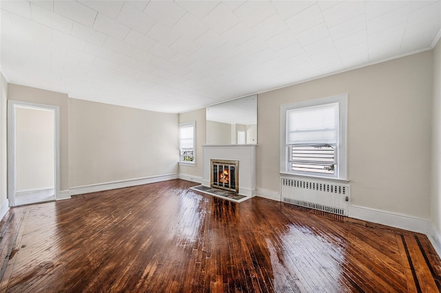 10 Leach St, Lynbrook, NY 11563 - unfurnished living room with radiator heating unit, hardwood / wood-style flooring, a glass covered fireplace, and crown molding