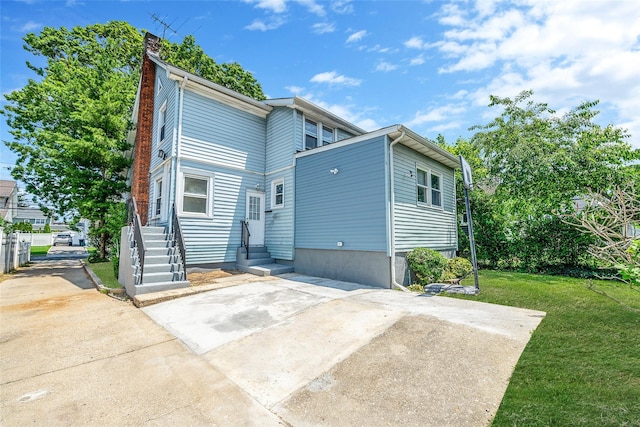 10 Leach St, Lynbrook, NY 11563 - rear view of property with entry steps, a chimney, and a lawn
