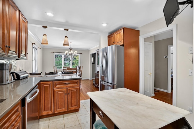 34 Winter Hill Rd, Tuckahoe, NY 10707 - kitchen featuring stainless steel appliances, a peninsula, brown cabinetry, light stone countertops, and ornamental molding