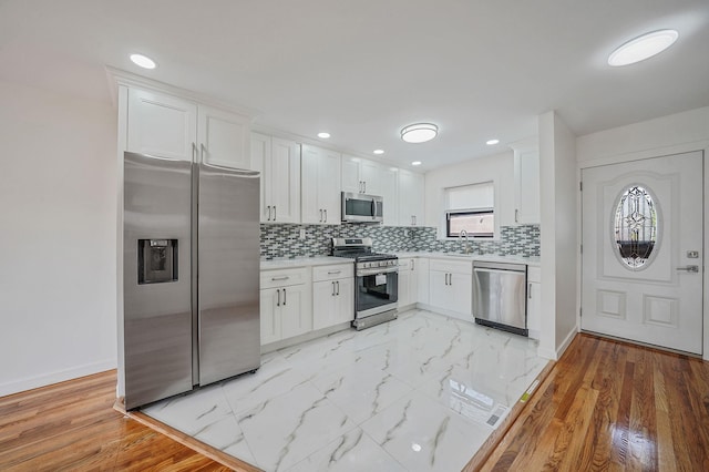11708A 233rd St, Cambria Heights, NY 11411 - kitchen featuring stainless steel appliances, white cabinetry, light countertops, decorative backsplash, and recessed lighting