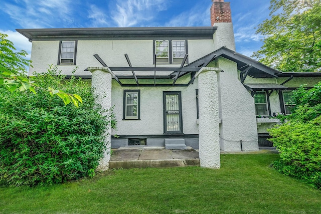 18803 Ilion Ave, Saint Albans, NY 11412 - back of house with stucco siding, a chimney, and a yard