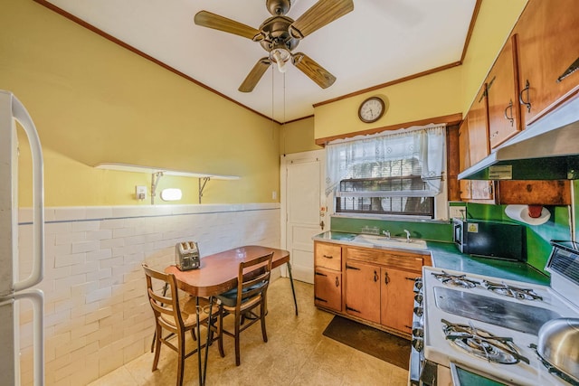 18803 Ilion Ave, Saint Albans, NY 11412 - kitchen with gas range gas stove, fridge, wainscoting, a ceiling fan, and brown cabinetry