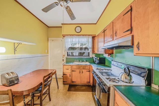 18803 Ilion Ave, Saint Albans, NY 11412 - kitchen with gas range oven, under cabinet range hood, ornamental molding, ceiling fan, and light countertops
