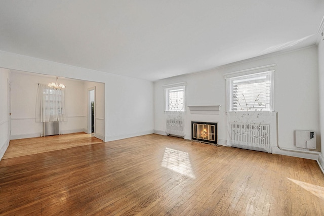 18803 Ilion Ave, Saint Albans, NY 11412 - unfurnished living room with a chandelier, radiator, a glass covered fireplace, and light wood-style floors