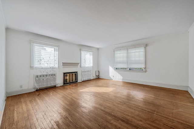 18803 Ilion Ave, Saint Albans, NY 11412 - unfurnished living room with radiator, hardwood / wood-style flooring, ornamental molding, and a glass covered fireplace