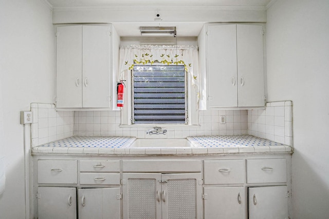 18803 Ilion Ave, Saint Albans, NY 11412 - kitchen with white cabinetry, tasteful backsplash, ornamental molding, and tile countertops