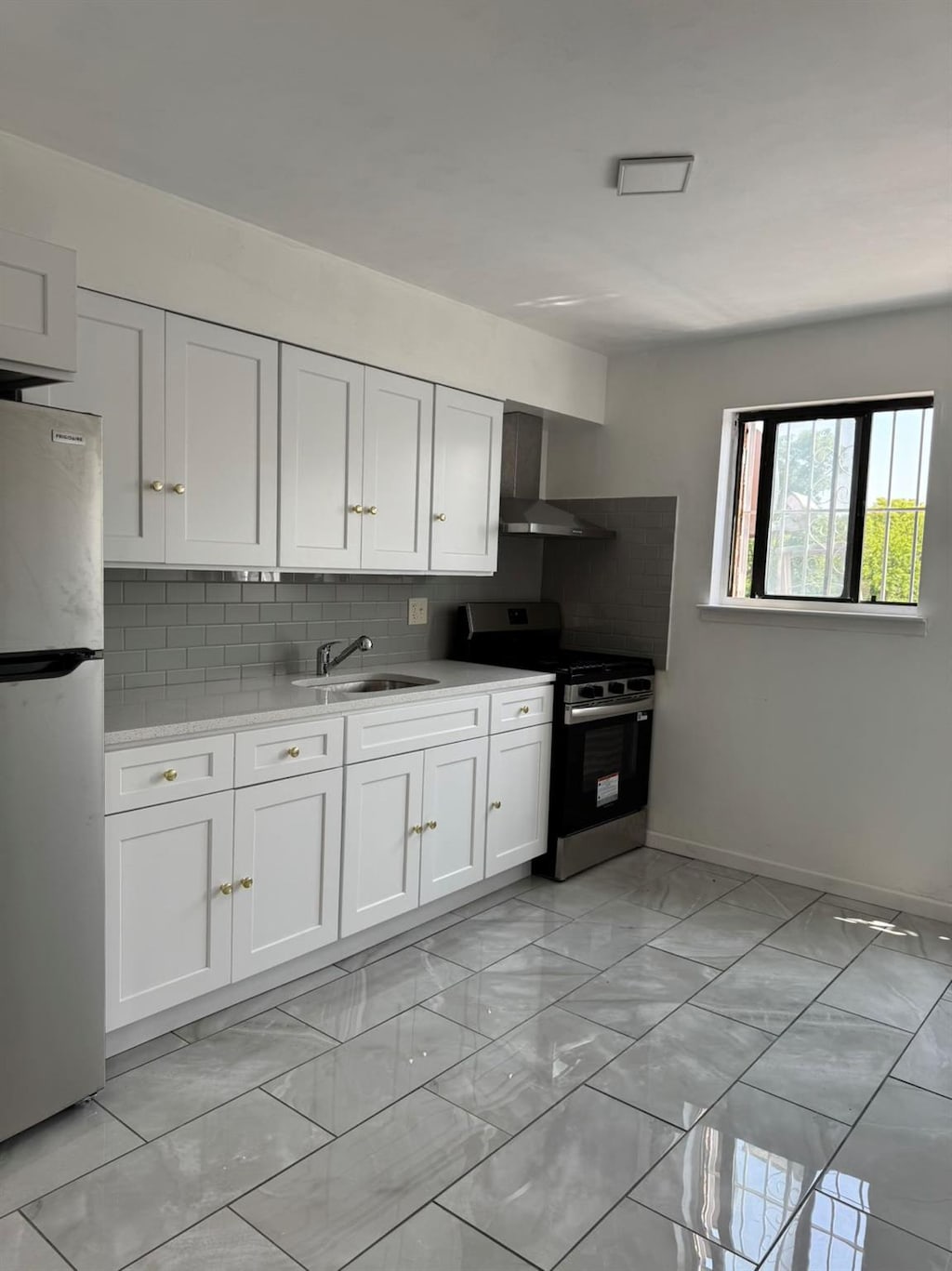 1811 123rd St Unit 4F, College Point, NY 11356 - kitchen featuring stainless steel appliances, wall chimney exhaust hood, light marble finish floors, light countertops, and decorative backsplash