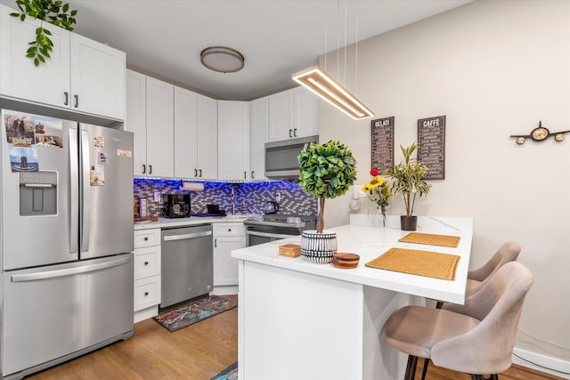 160-15 Powells Cove Blvd Unit B103, Beechhurst, NY 11357 - kitchen featuring stainless steel appliances, a peninsula, light countertops, and light wood-style flooring