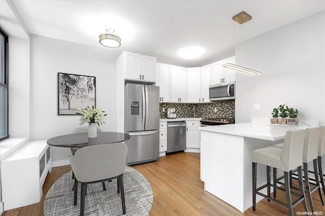 160-15 Powells Cove Blvd Unit B103, Beechhurst, NY 11357 - kitchen with stainless steel appliances, a peninsula, a kitchen bar, backsplash, and light countertops