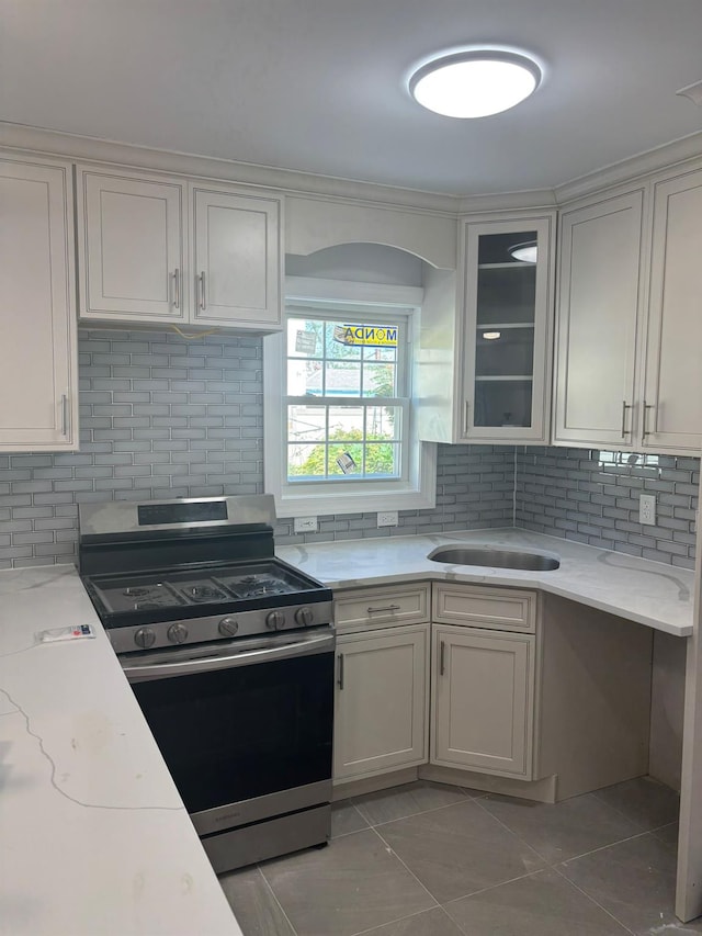 167-12 110th Ave, Jamaica, NY 11433 - kitchen with gas range, decorative backsplash, glass insert cabinets, light tile patterned flooring, and light stone countertops