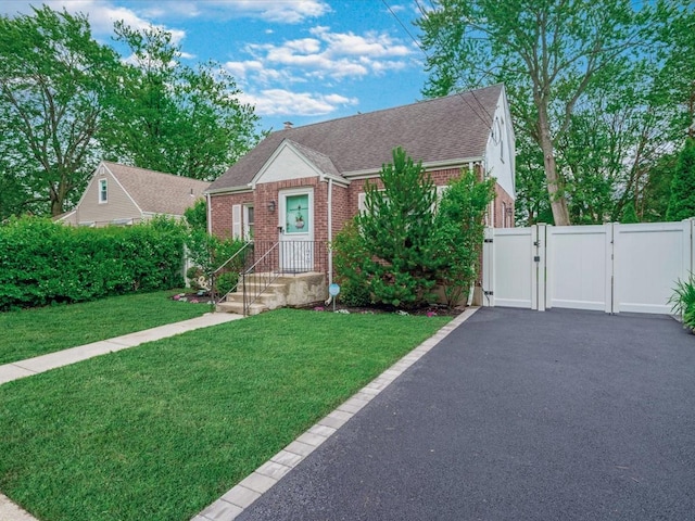 71 Van Nostrand Ave, North Merrick, NY 11566 - view of front facade featuring a gate, brick siding, a shingled roof, and driveway