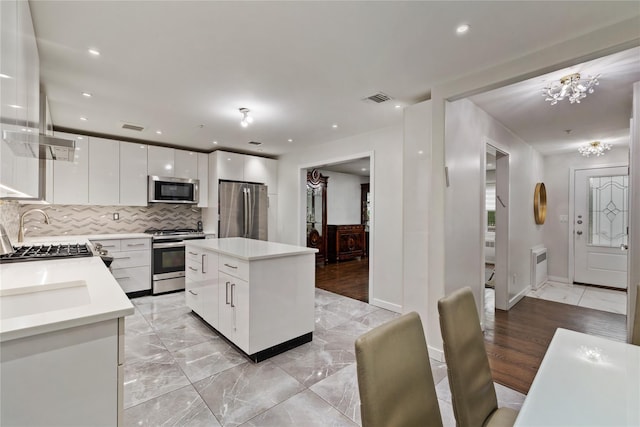 487 W Central Ave Unit 112, Spring Valley, NY 10977 - kitchen with appliances with stainless steel finishes, tasteful backsplash, white cabinets, light countertops, and a chandelier