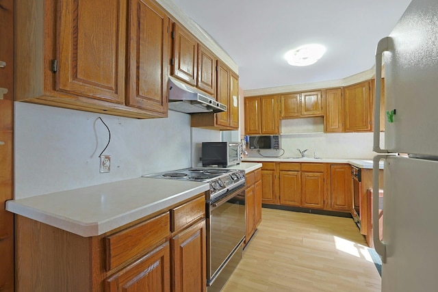 328 Willis Ave, Hawthorne, NY 10532 - kitchen with black appliances, under cabinet range hood, light wood-style flooring, light countertops, and brown cabinetry