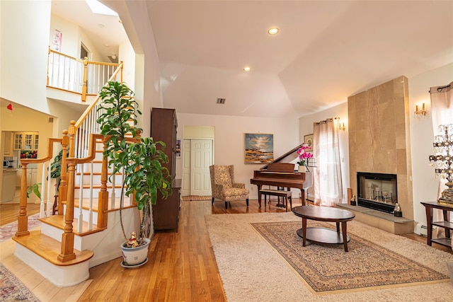 53 Vista Hill Rd, Great Neck, NY 11021 - living room featuring light wood-style flooring, a tiled fireplace, high vaulted ceiling, stairs, and recessed lighting