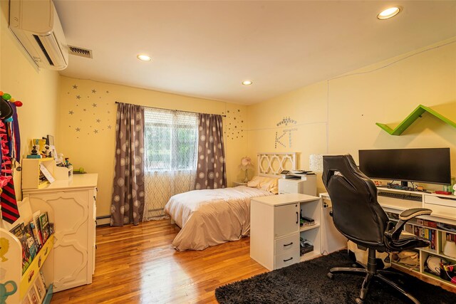 53 Vista Hill Rd, Great Neck, NY 11021 - bedroom featuring a wall unit AC, wood finished floors, recessed lighting, an office area, and a baseboard radiator