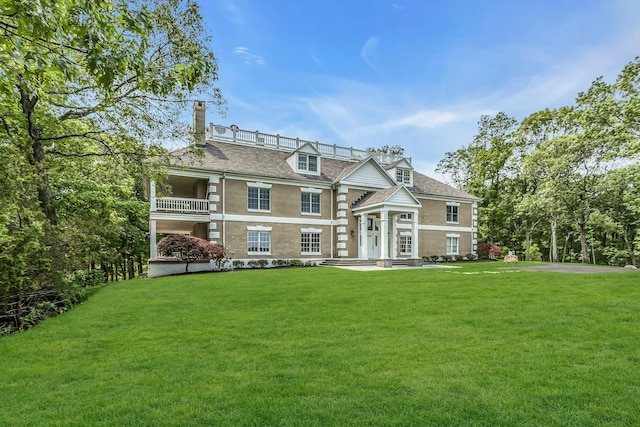 12 Orient Ave, Northport, NY 11768 - view of front of home with a chimney, a front lawn, and a balcony