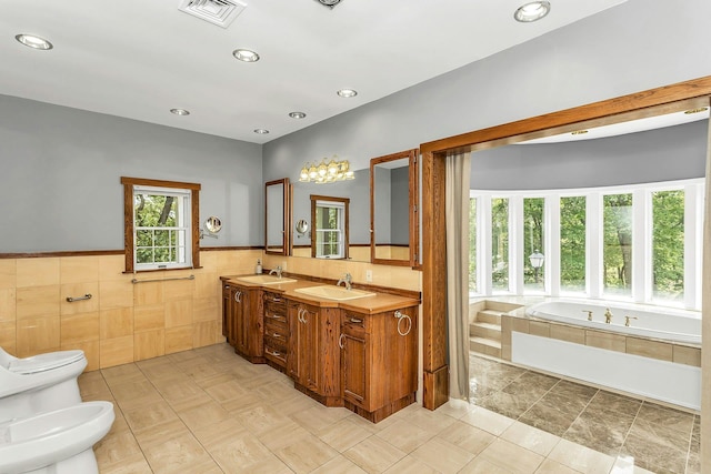 12 Orient Ave, Northport, NY 11768 - bathroom featuring a bidet, tile walls, a garden tub, double vanity, and wainscoting