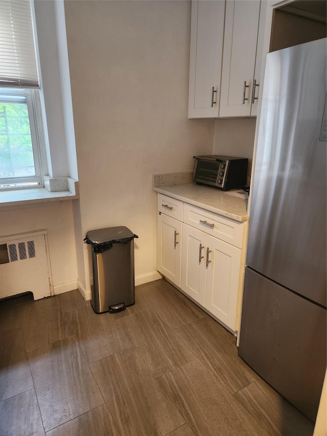 60 Knolls Cres Unit 1F, Bronx, NY 10463 - kitchen with freestanding refrigerator, radiator, white cabinets, and light stone counters