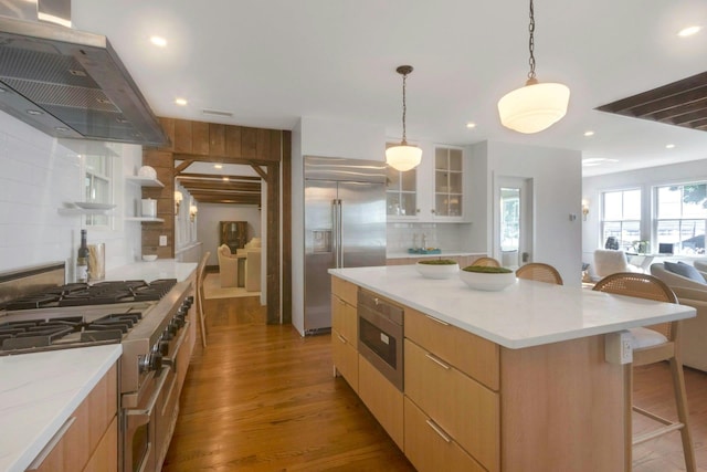 115 River Rd, Nyack, NY 10960 - kitchen featuring built in appliances, exhaust hood, a kitchen bar, wood finished floors, and recessed lighting
