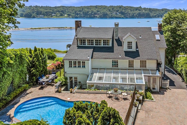 50 Shore Rd, Cold Spring Harbor, NY 11724 - back of house featuring a sunroom, a chimney, an outdoor pool, a patio area, and a water view