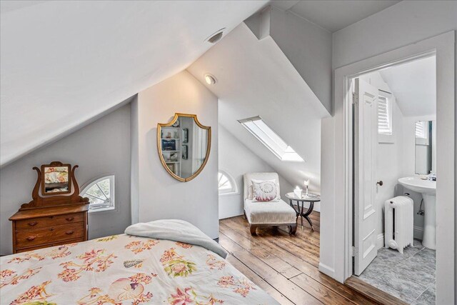 50 Shore Rd, Cold Spring Harbor, NY 11724 - bedroom featuring vaulted ceiling, radiator, wood-type flooring, a skylight, and connected bathroom