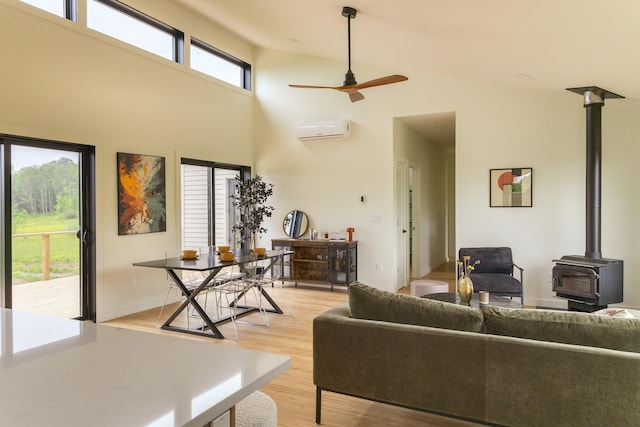 612 Beechwoods Rd, Callicoon, NY 12723 - living area featuring an AC wall unit, a wood stove, a ceiling fan, light wood-style flooring, and a towering ceiling