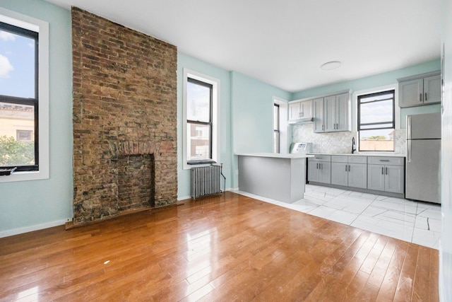 6050 71st Ave, Ridgewood, NY 11385 - unfurnished living room with radiator heating unit and light wood-style flooring