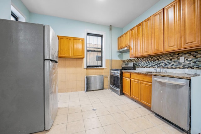 6050 71st Ave, Ridgewood, NY 11385 - kitchen with stainless steel appliances, radiator heating unit, under cabinet range hood, light tile patterned floors, and light stone countertops